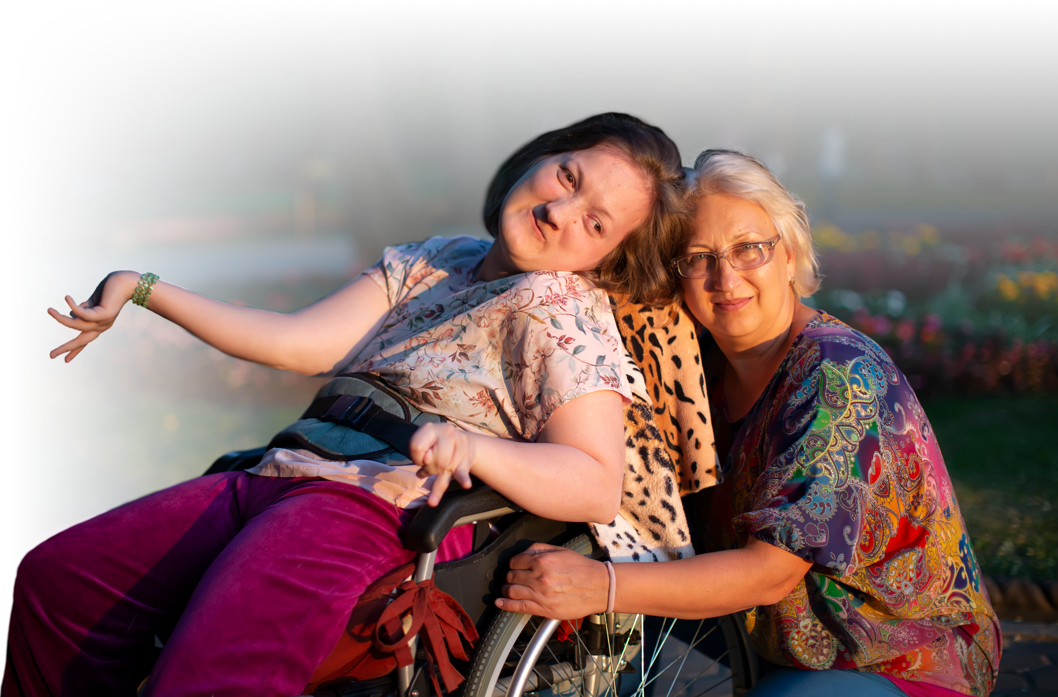 Photo of an adult daughter in a wheelchair with her older mother together smilling.